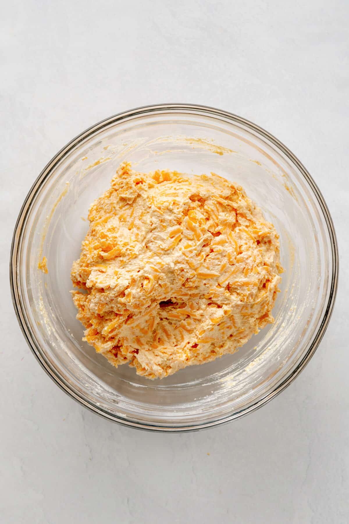 shredded cheddar cheese, mayo, cream cheese, seasonings in a large glass bowl.