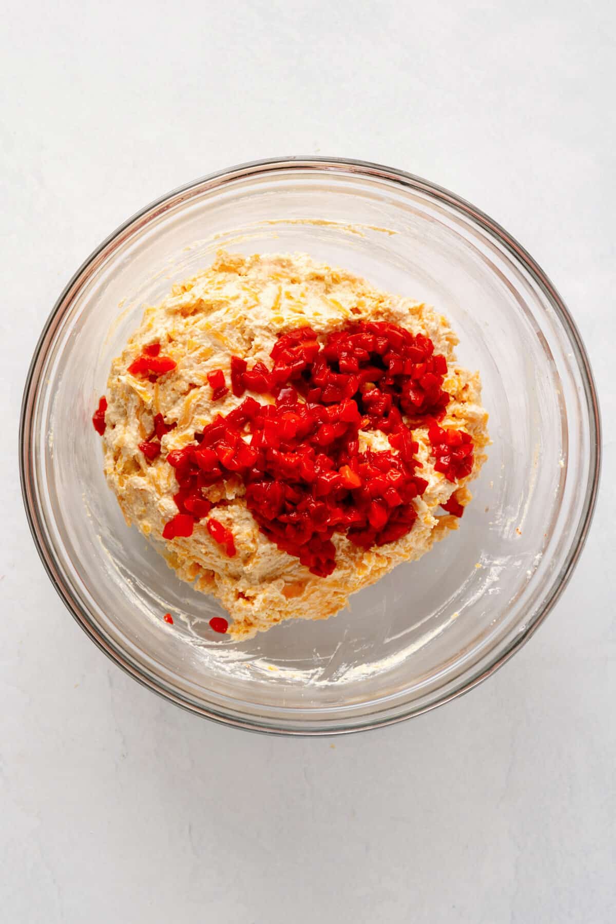 shredded cheddar cheese, mayo, cream cheese, seasonings, and pimentos in a large glass bowl.
