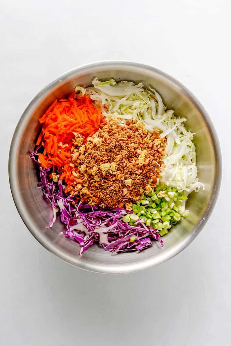 stainless steel mixing bowl with shredded veggies and the toasted crushed ramen noodles