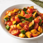 A bowl of sautéed zucchini and tomatoes.