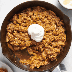 Overhead image of a skillet apple crisp topped with whipped cream.
