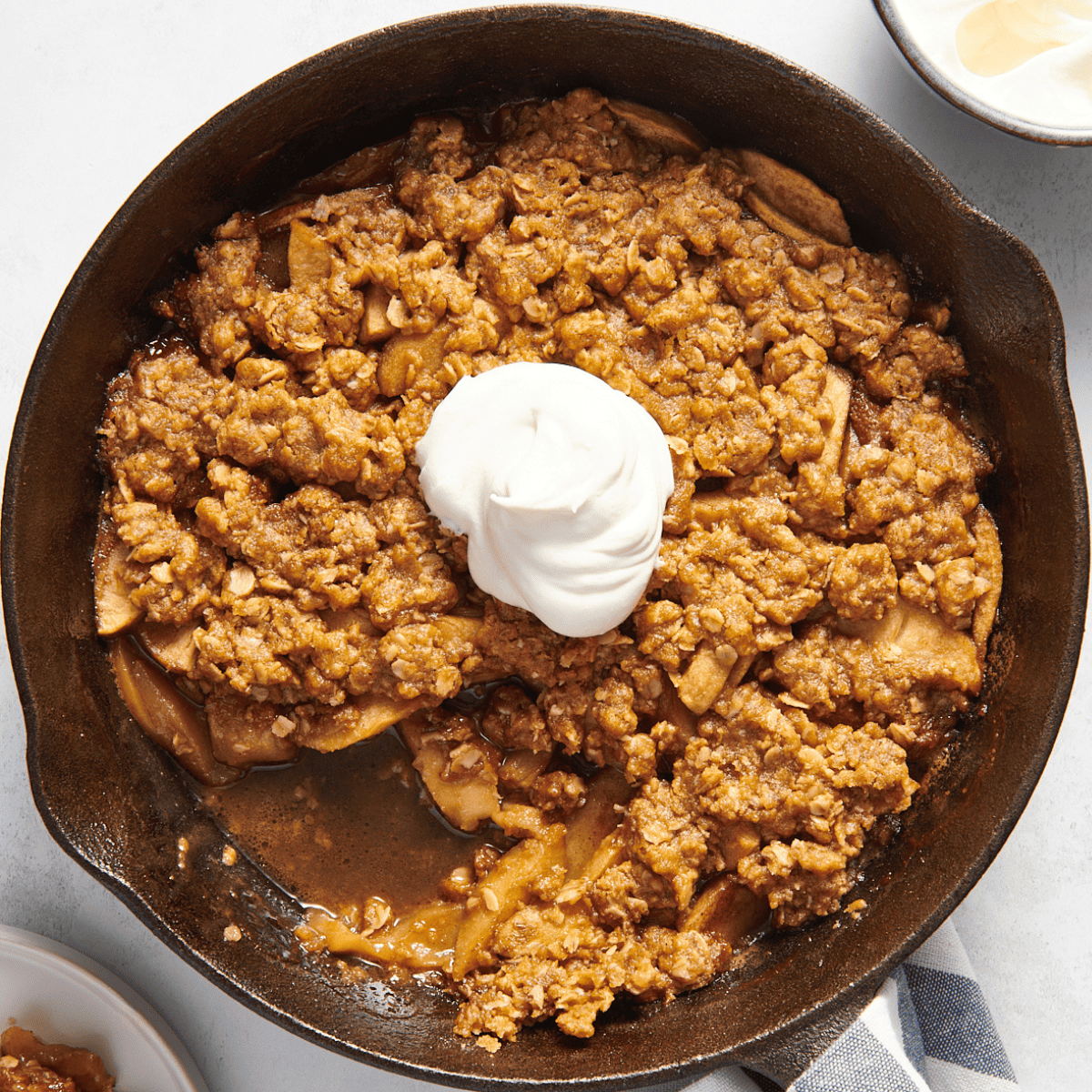 Overhead image of a skillet apple crisp topped with whipped cream.
