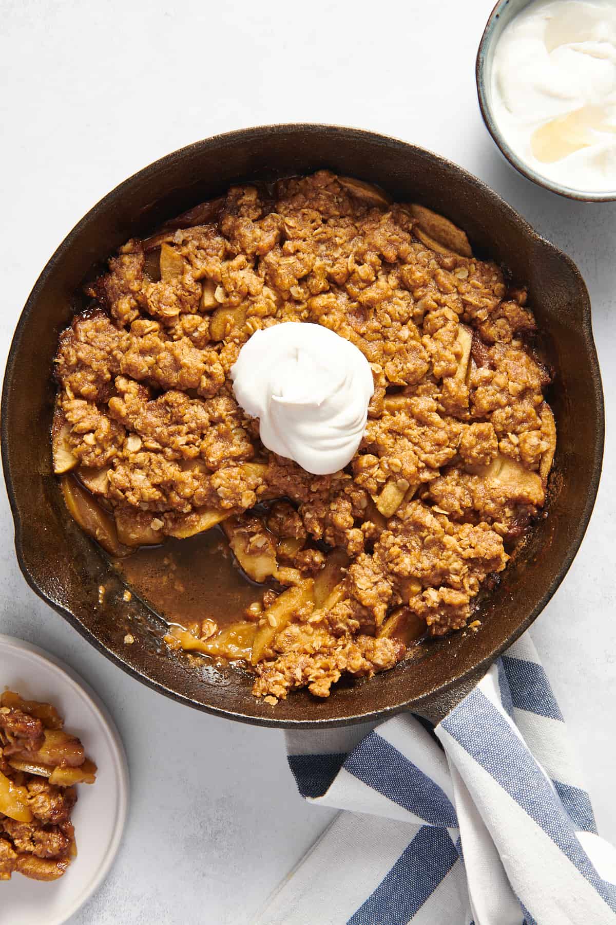 top down image of skillet apple crisp topped with a scoop of vanilla ice cream 