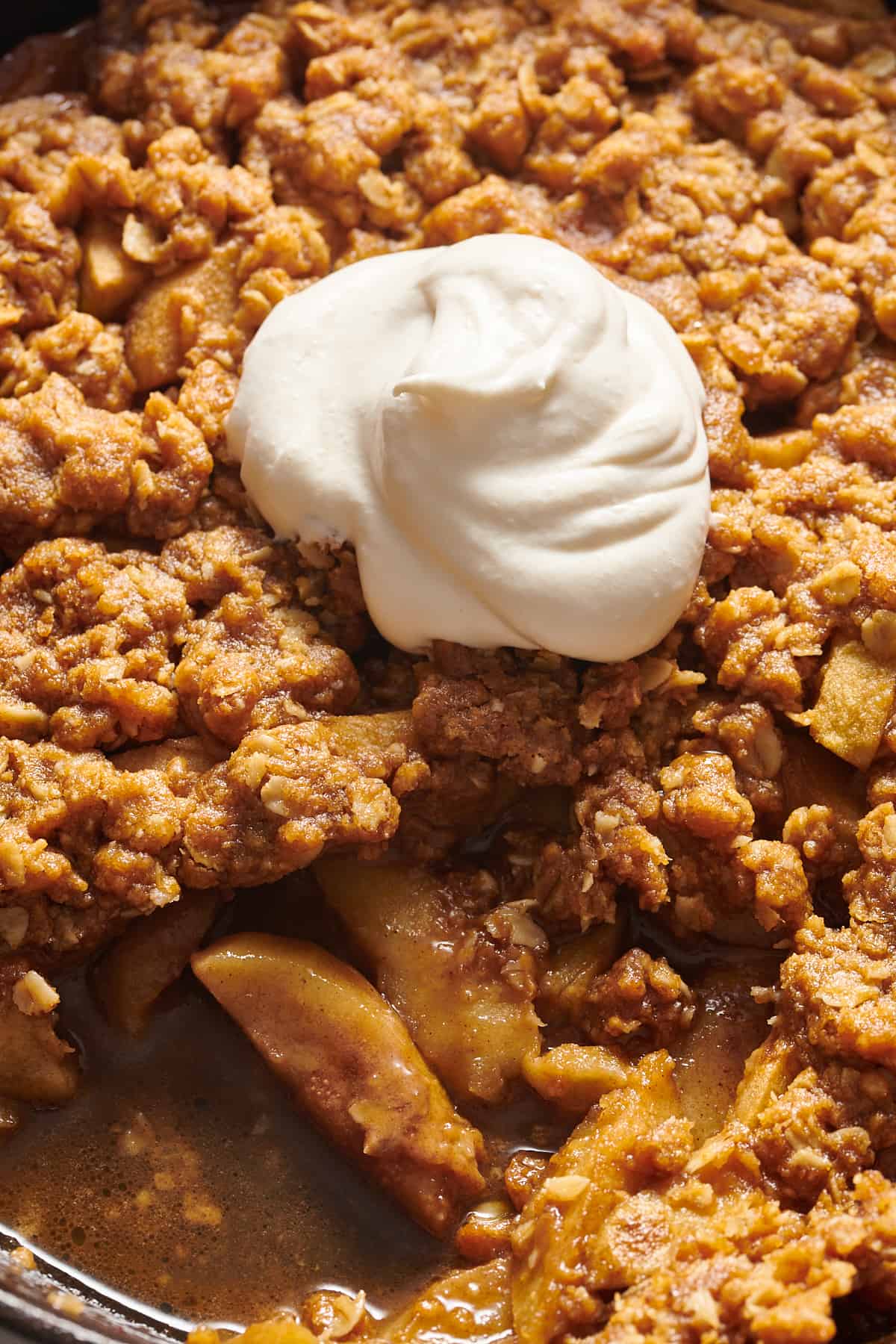 close up image of skillet apple crisp topped with a scoop of vanilla ice cream