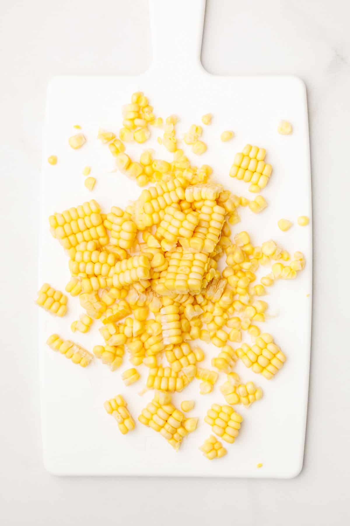 corn cut off the cob sitting on a white cutting board