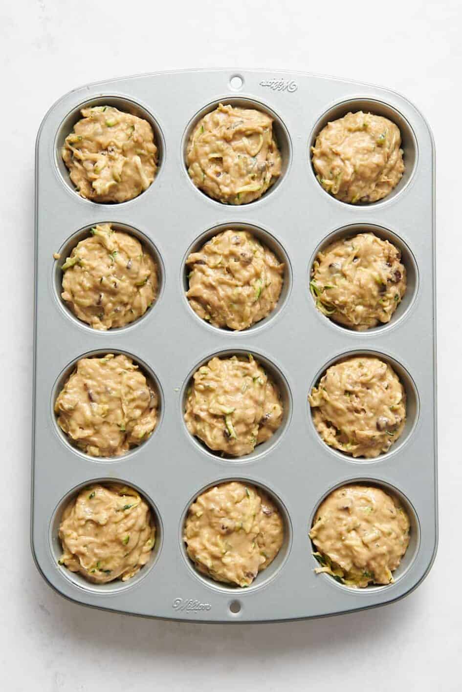12 zucchini muffin prepared in a muffin tin ready to bake