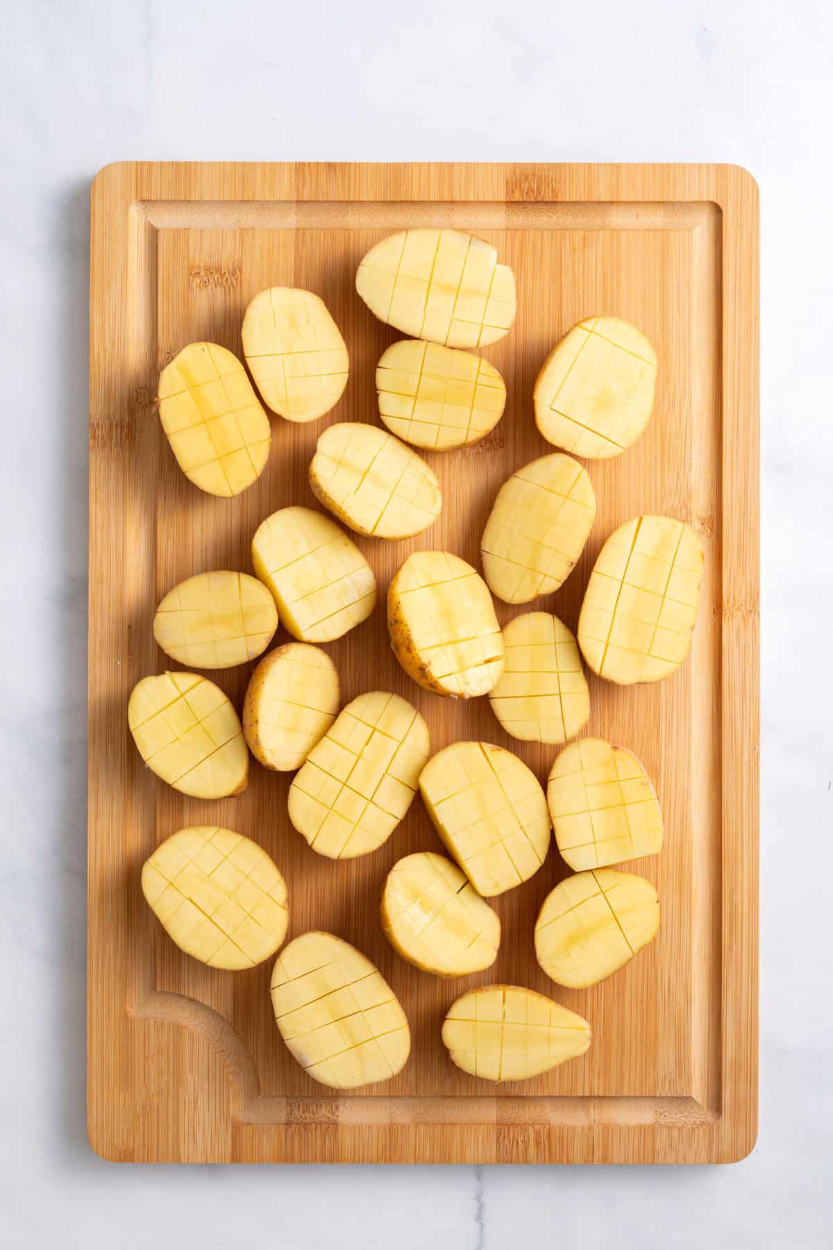 small gold potatoes cut in half long ways and scored vertically and horizontally