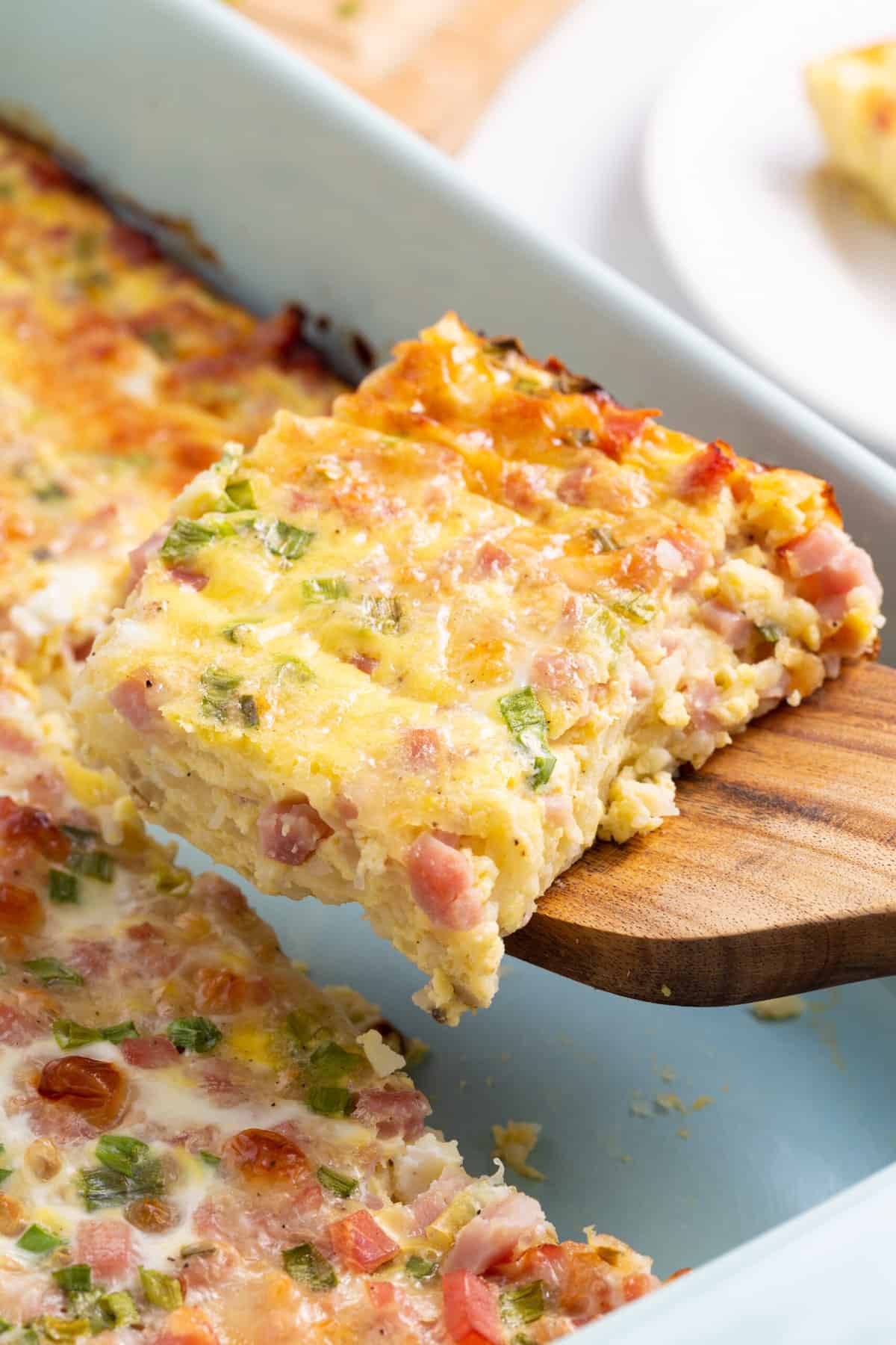 close up image of a square slice of farmer's breakfast casserole sitting on a wooden spatula