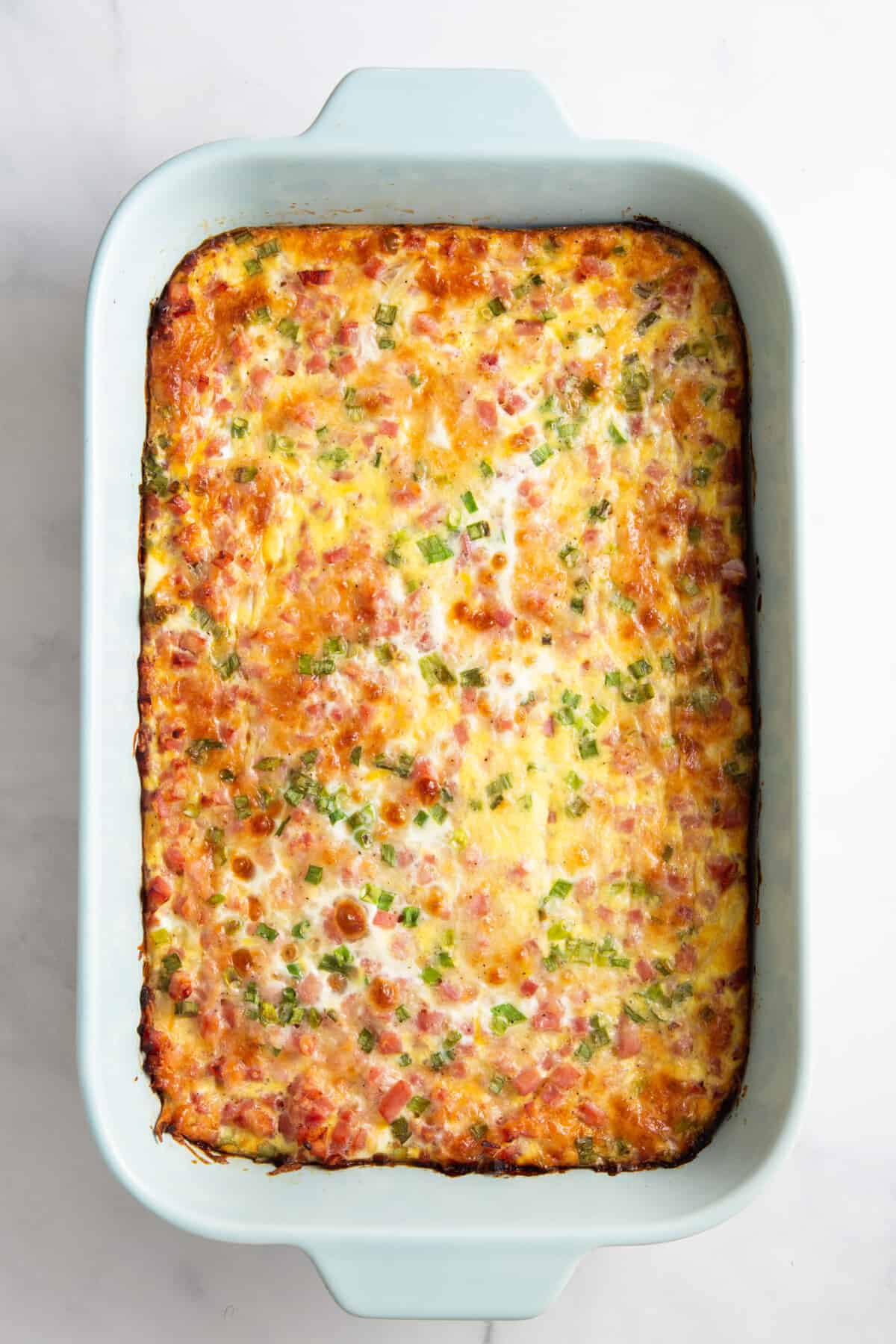 baked farmer's breakfast casserole sitting in a light blue 9x13 casserole dish