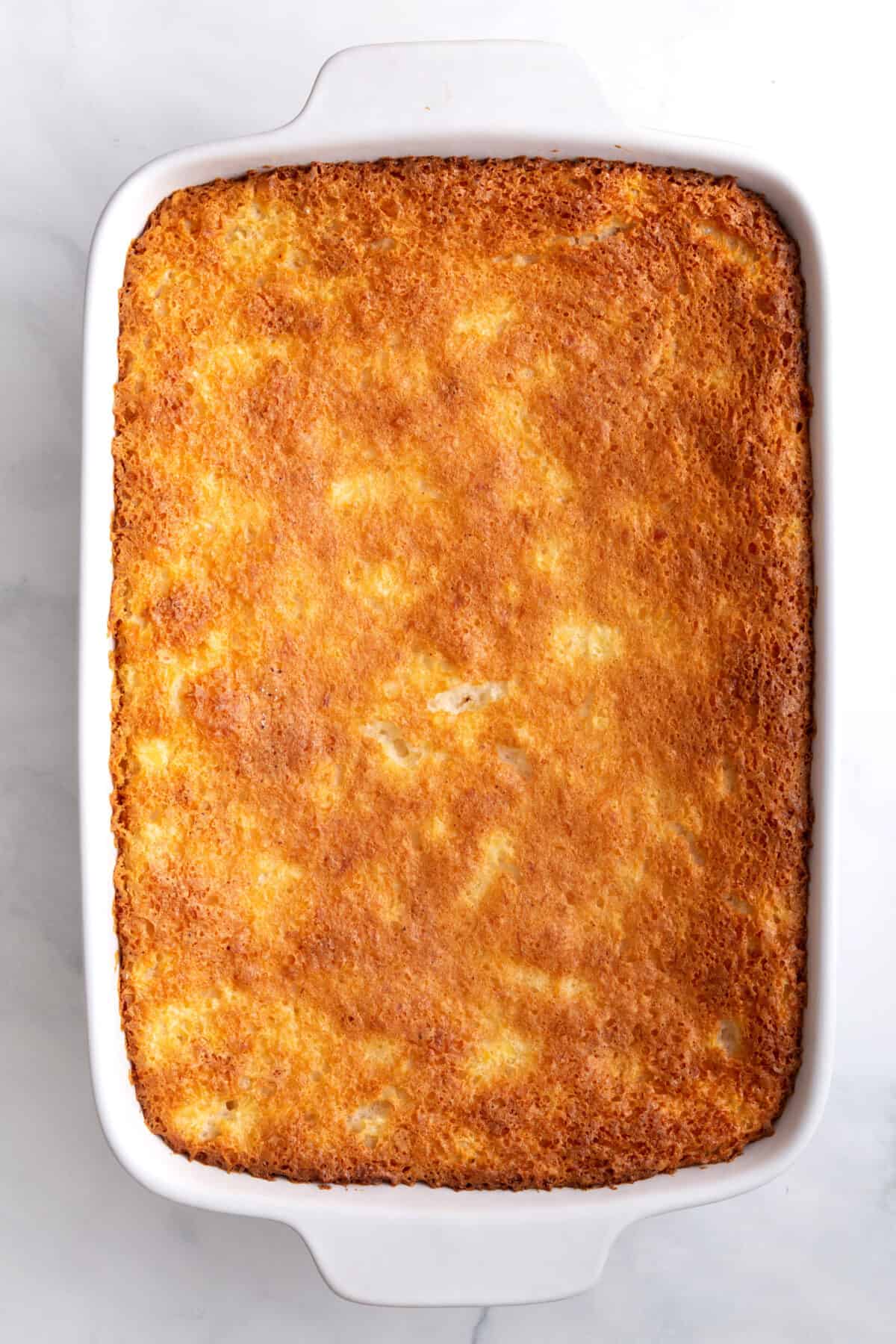 baked pineapple angel food cake sitting in a 9x13 baking dish