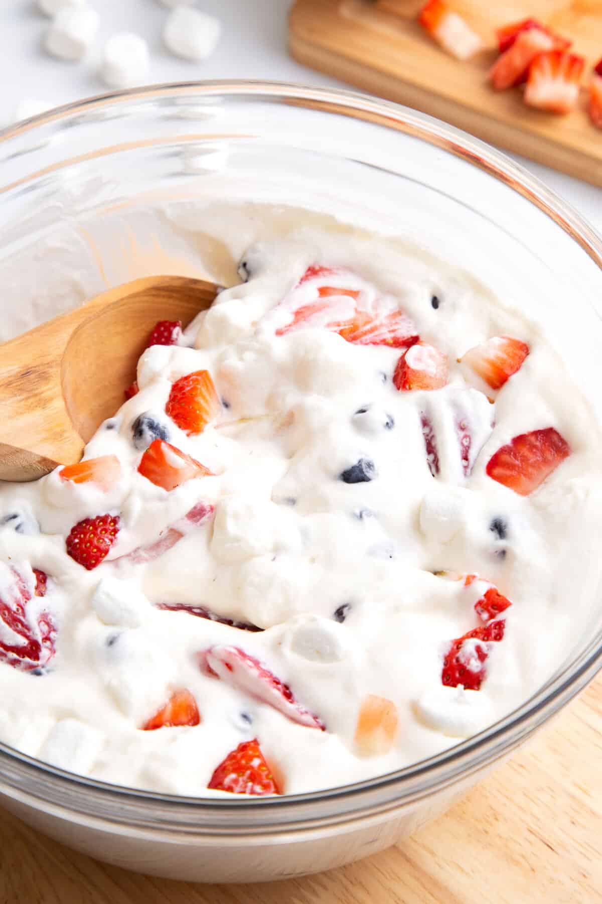 close up image of a large glass bowl of red white and blue cheesecake salad