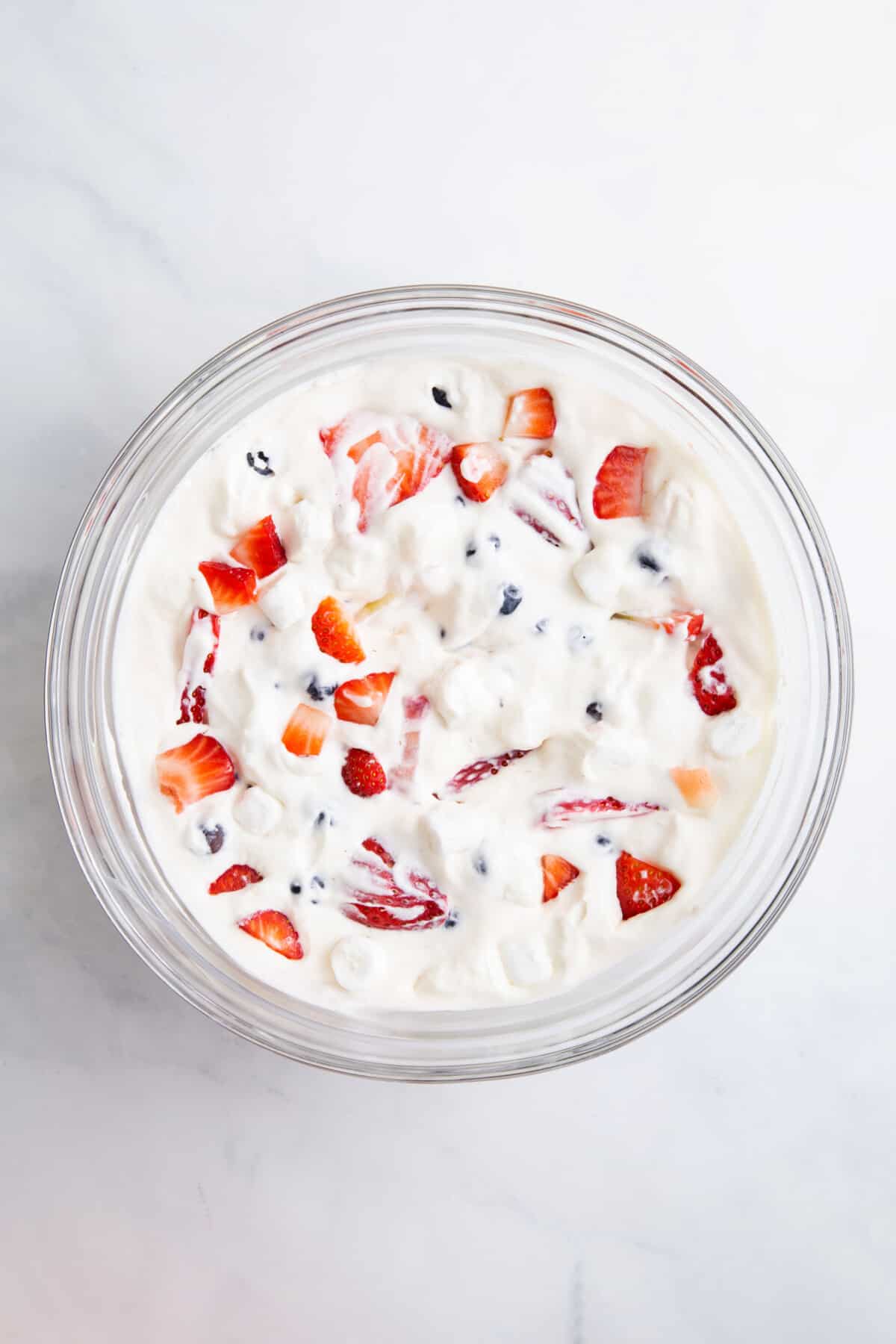 large glass bowl of red white and blue cheesecake salad.