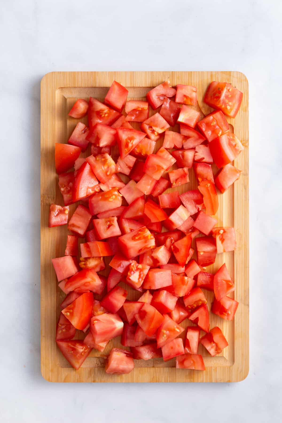 chopped tomatoes sitting on a wood cutting board