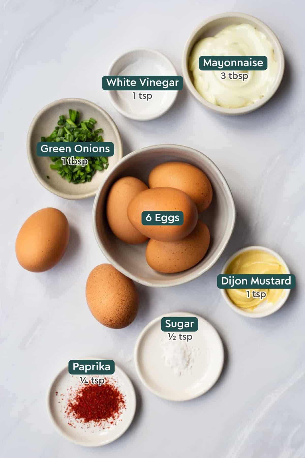 All of the ingredients for classic deviled eggs in bowls on a countertop.