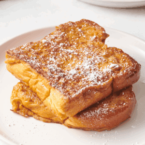 Two pieces of eggnog French toast topped with powdered sugar.