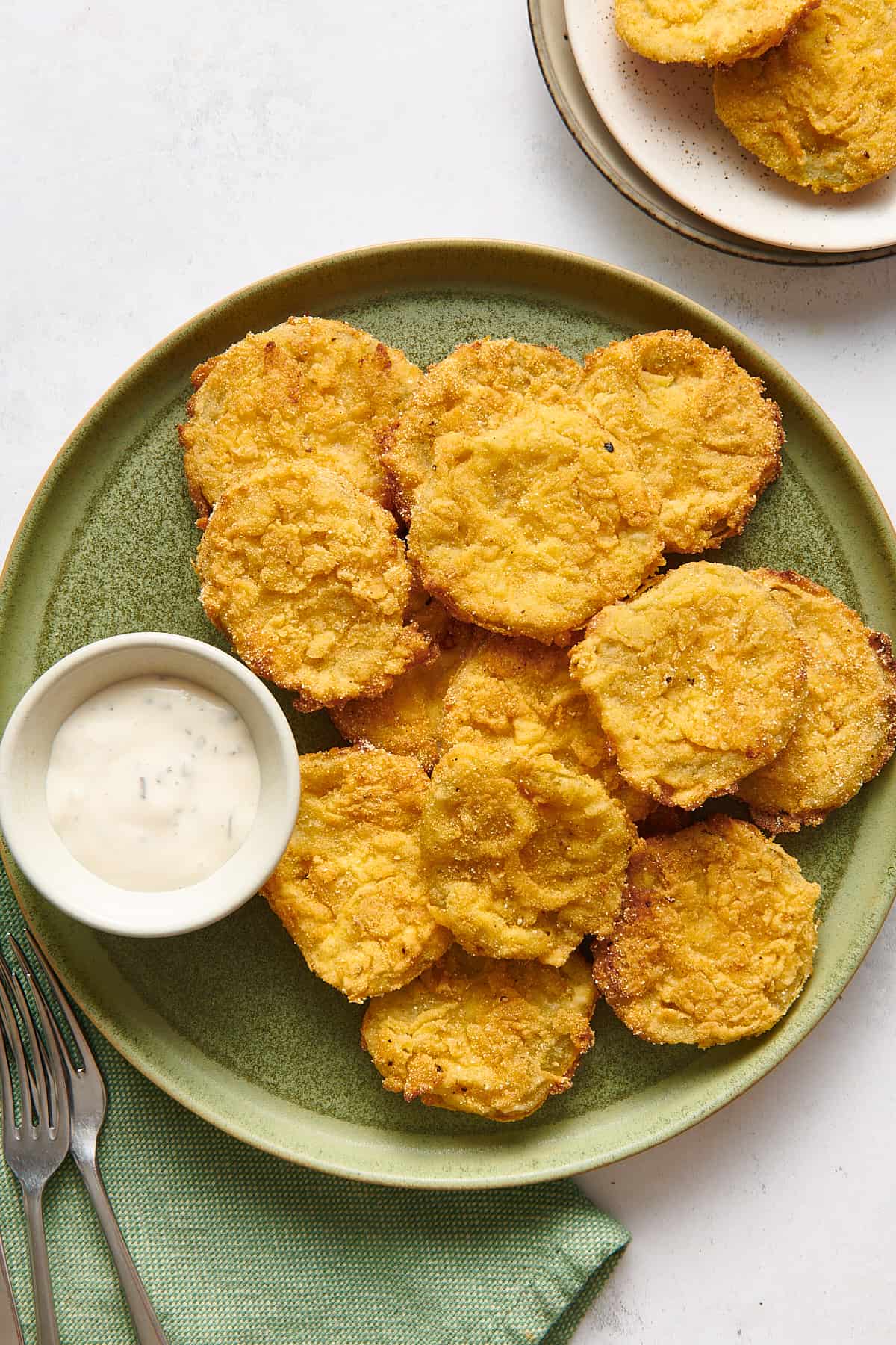 top down image of fried green tomatoes served on a green round plate with a side dish of ranch dressing