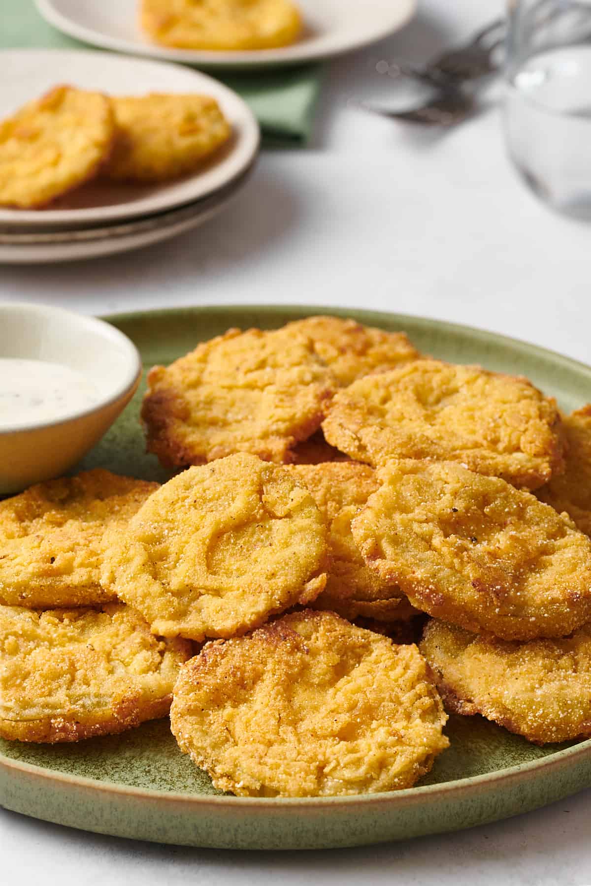 fried green tomatoes served on a green round plate with a side dish of ranch dressing