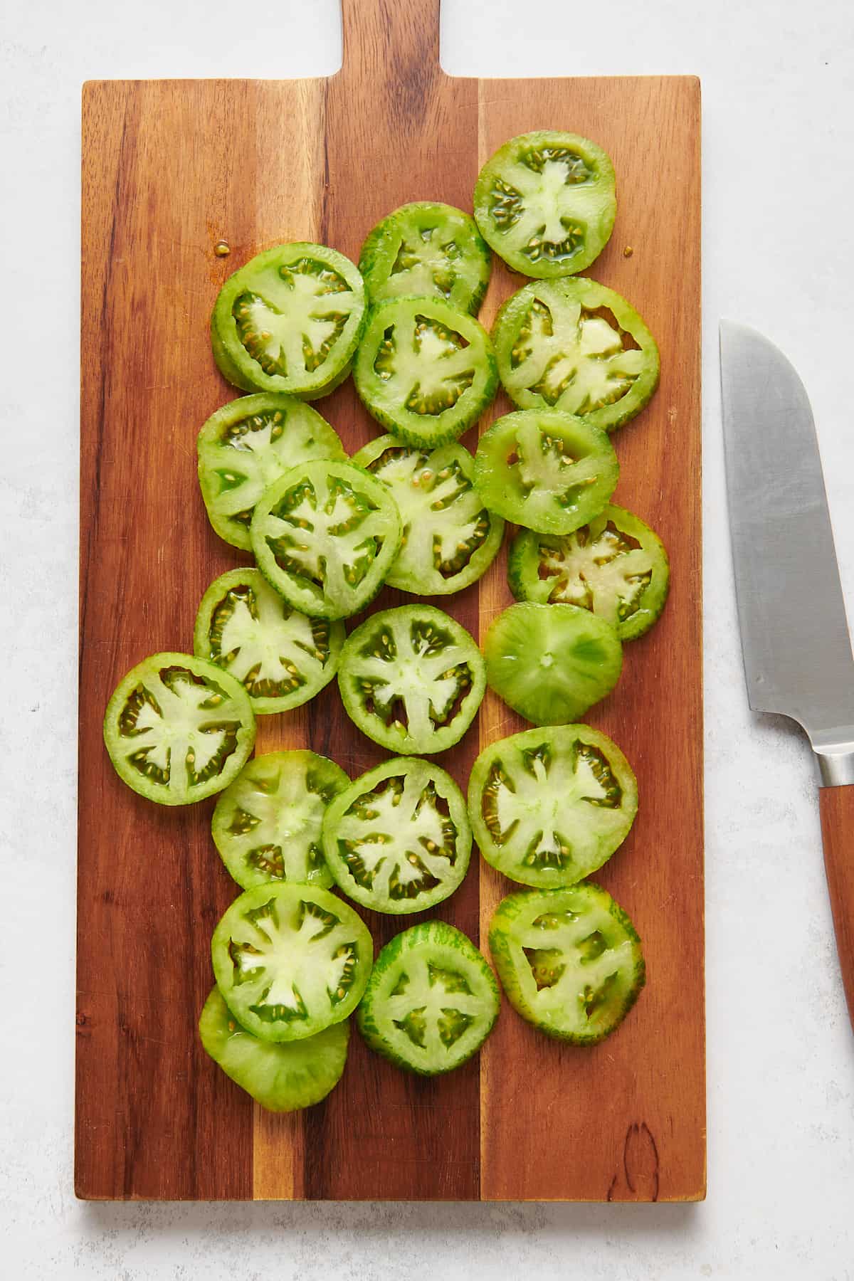 sliced green tomatoes sitting on a wooden cutting board