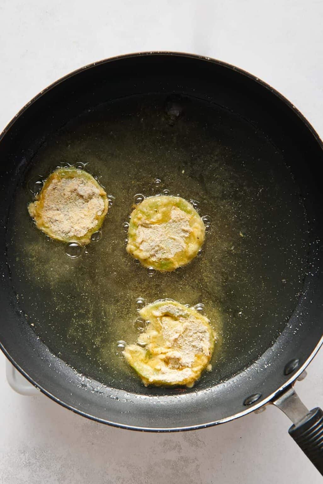 battered sliced green tomatoes shallow frying in a large skillet