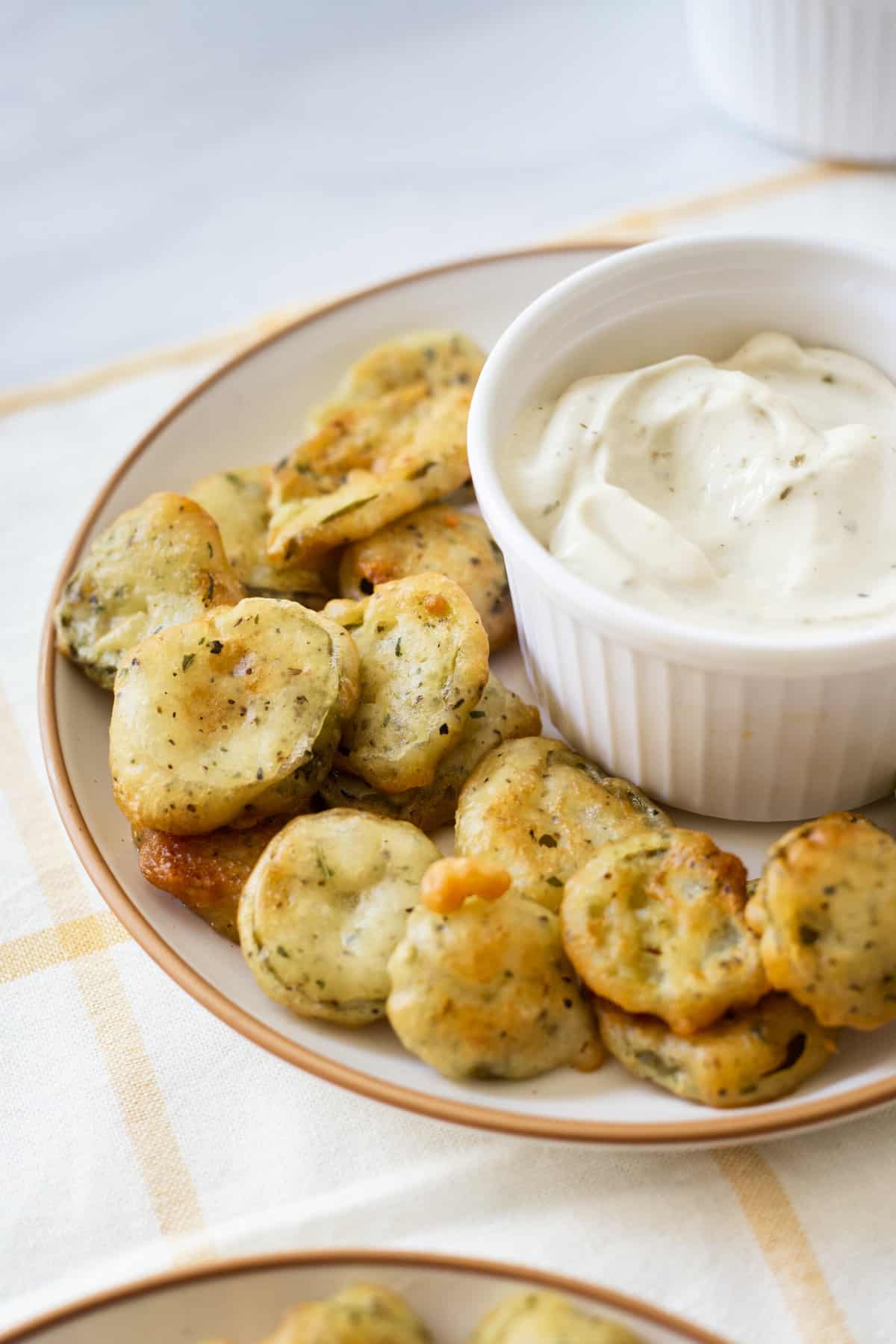 round plate of fried pickles with a ceramic side dish of ranch dressing for dipping