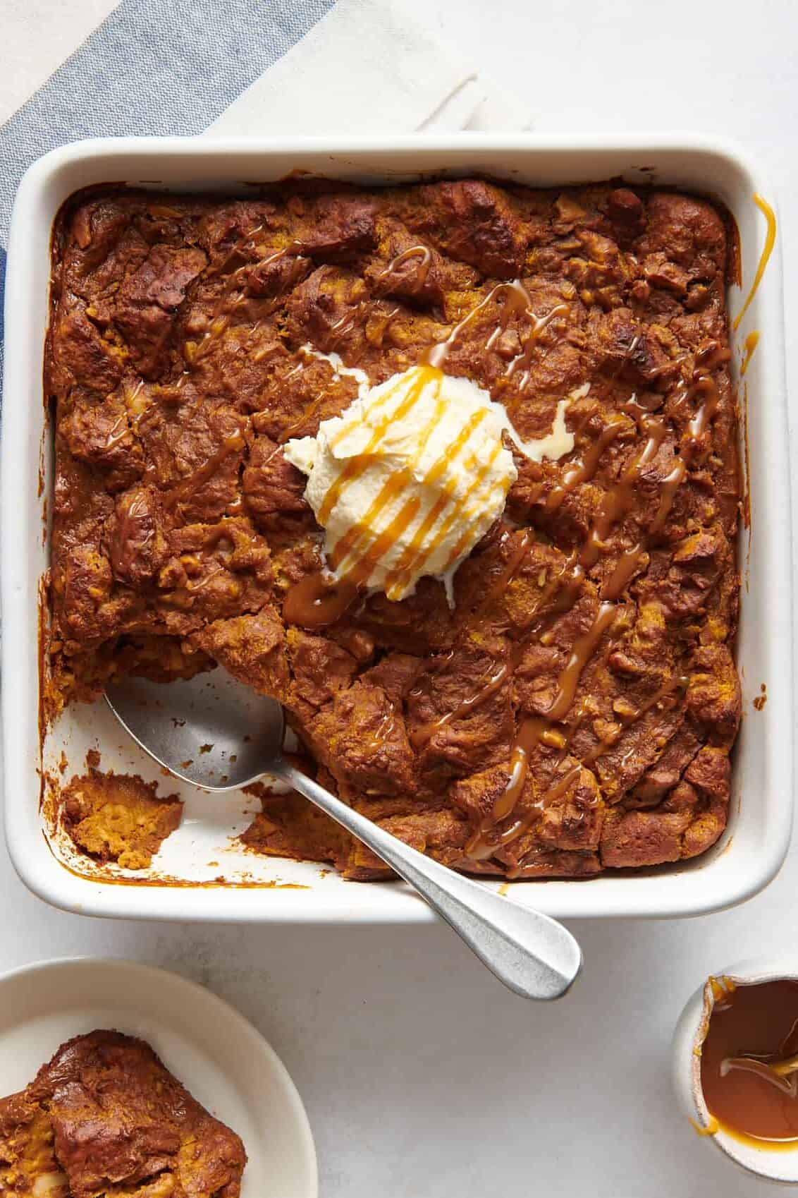 top down image of pumpkin bread pudding sitting in a 8x8 casserole dish topped with vanilla ice cream and caramel