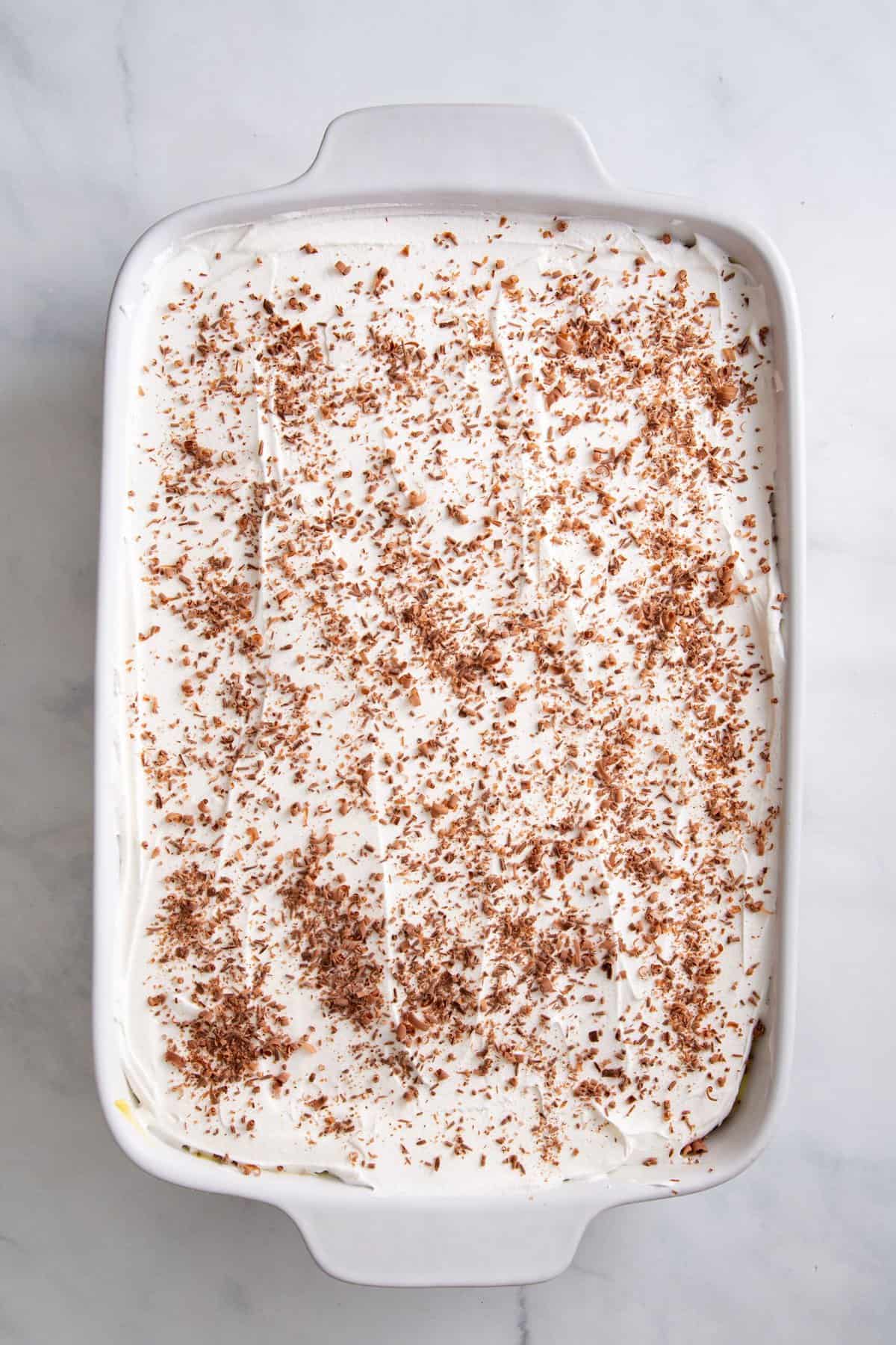 cool whip layered evenly topped with chocolate shavings sitting in a 9x13 baking dish