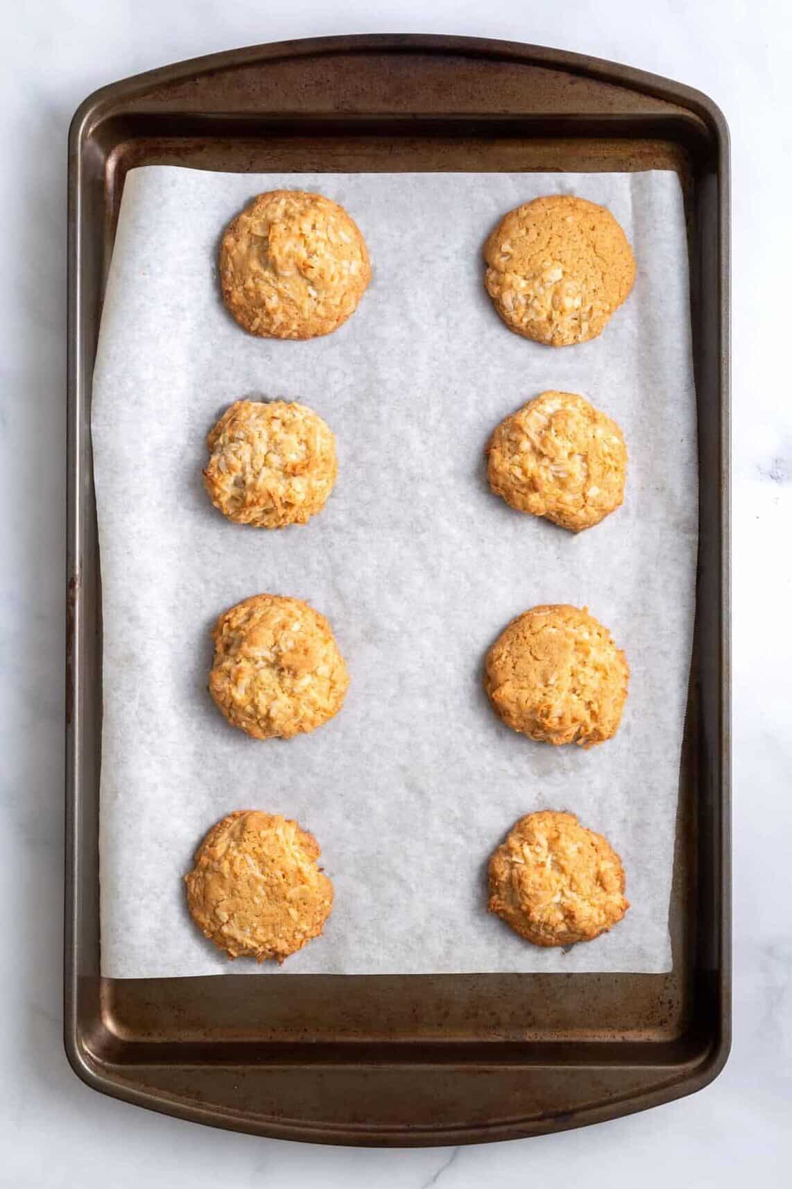 eight baked coconut cookies sitting on a baking tray with a baking sheet 