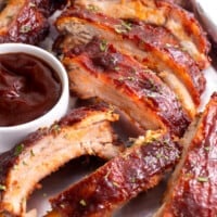 Crock pot ribs on a plate with a small bowl of BBQ sauce.