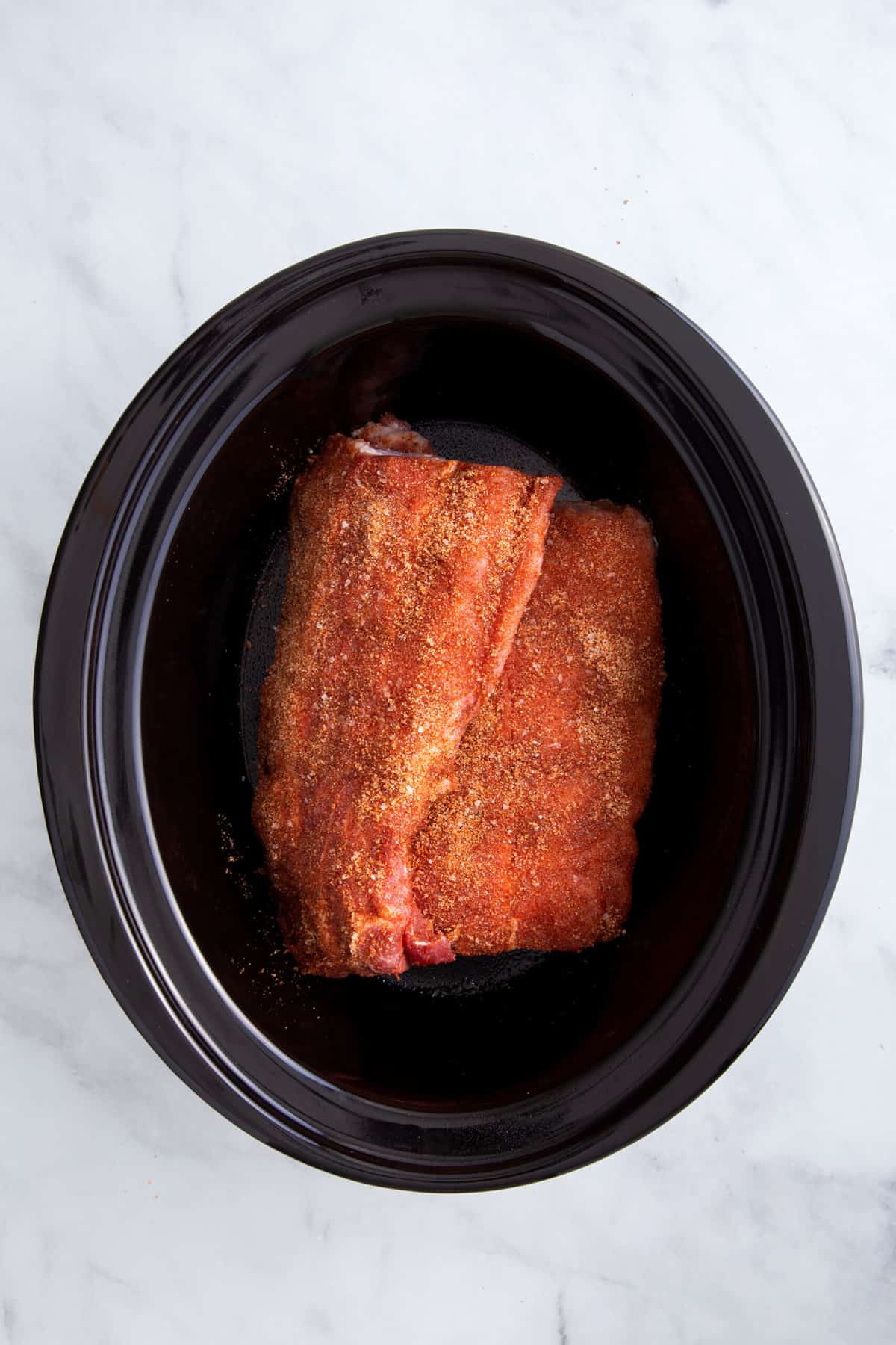 dry rubbed pork ribs sitting in a slow cooker