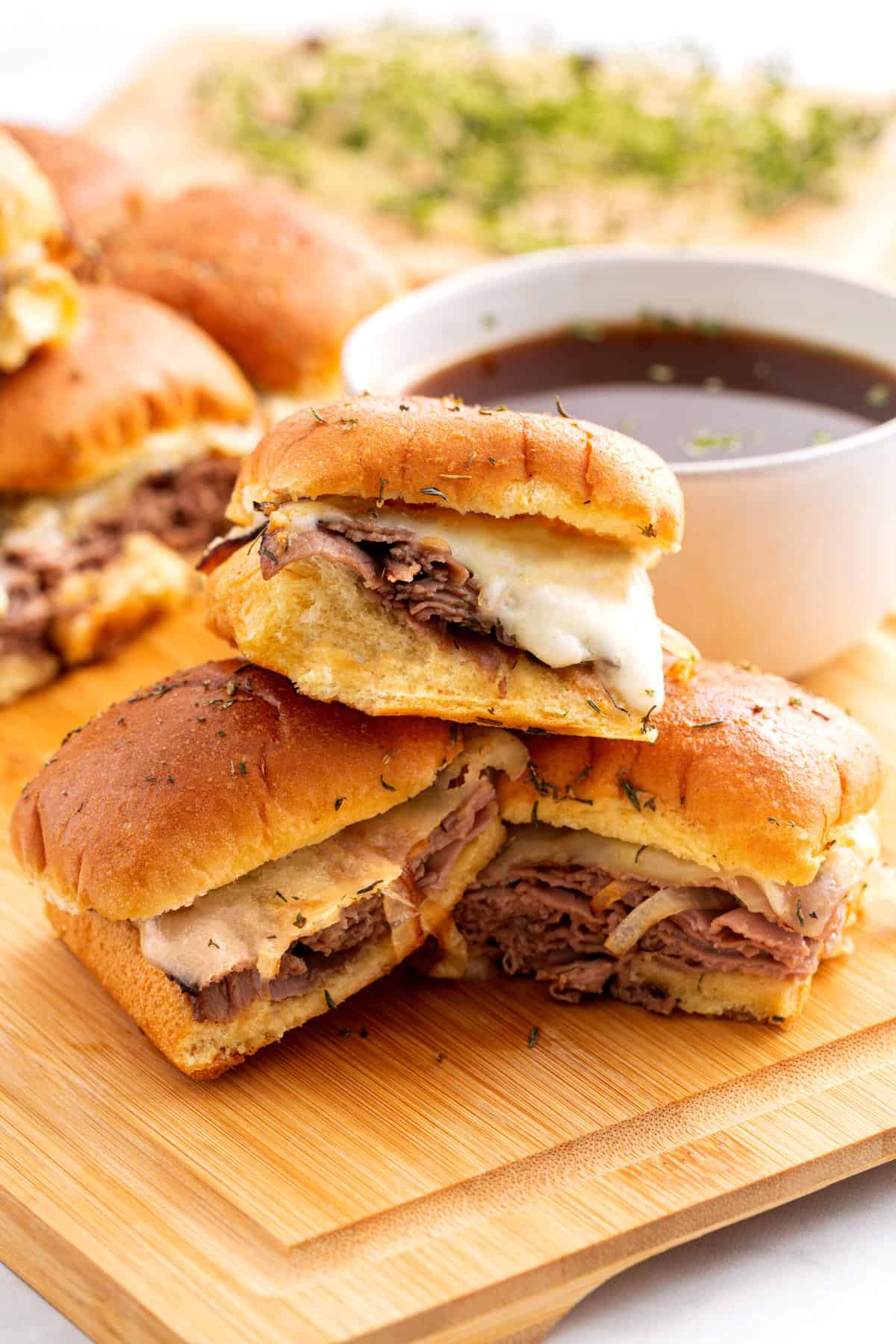 stack of french dip sliders sitting on a wooden cutting board