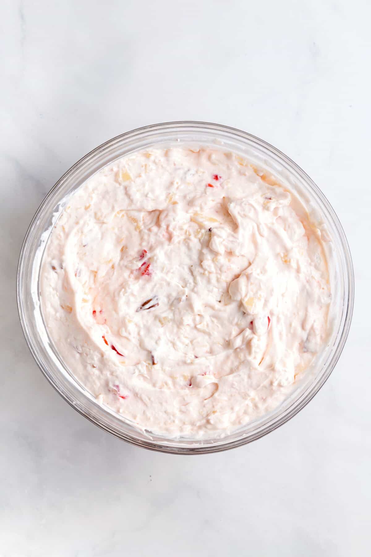cool whip, cream cheese, condensed milk and chopped cherries, pecans and shredded coconut mixed together in a large glass bowl.