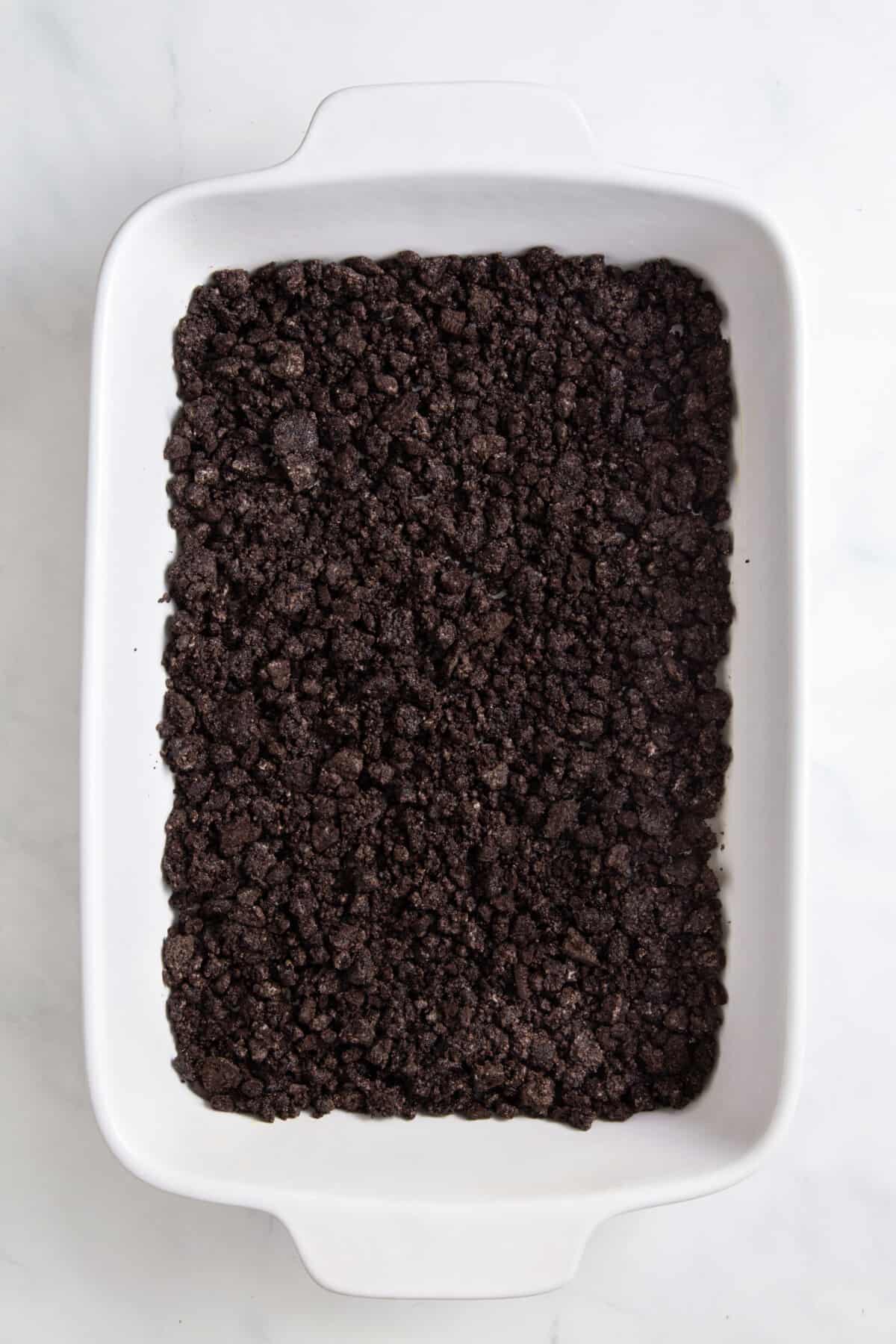 crushed oreo crumbs sitting in a 9x13 casserole dish.