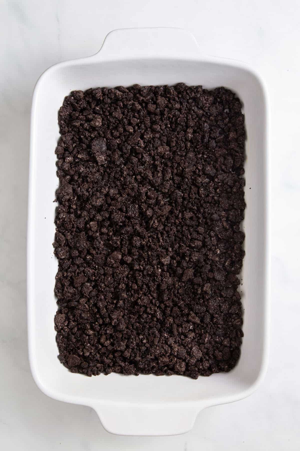crushed oreo crumbs sitting in a 9x13 casserole dish