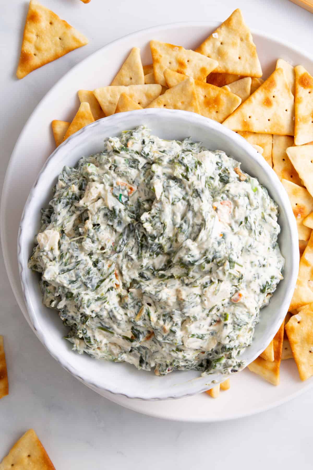 top down image of a bowl of spinach dip with a side of triangle shaped pita chips