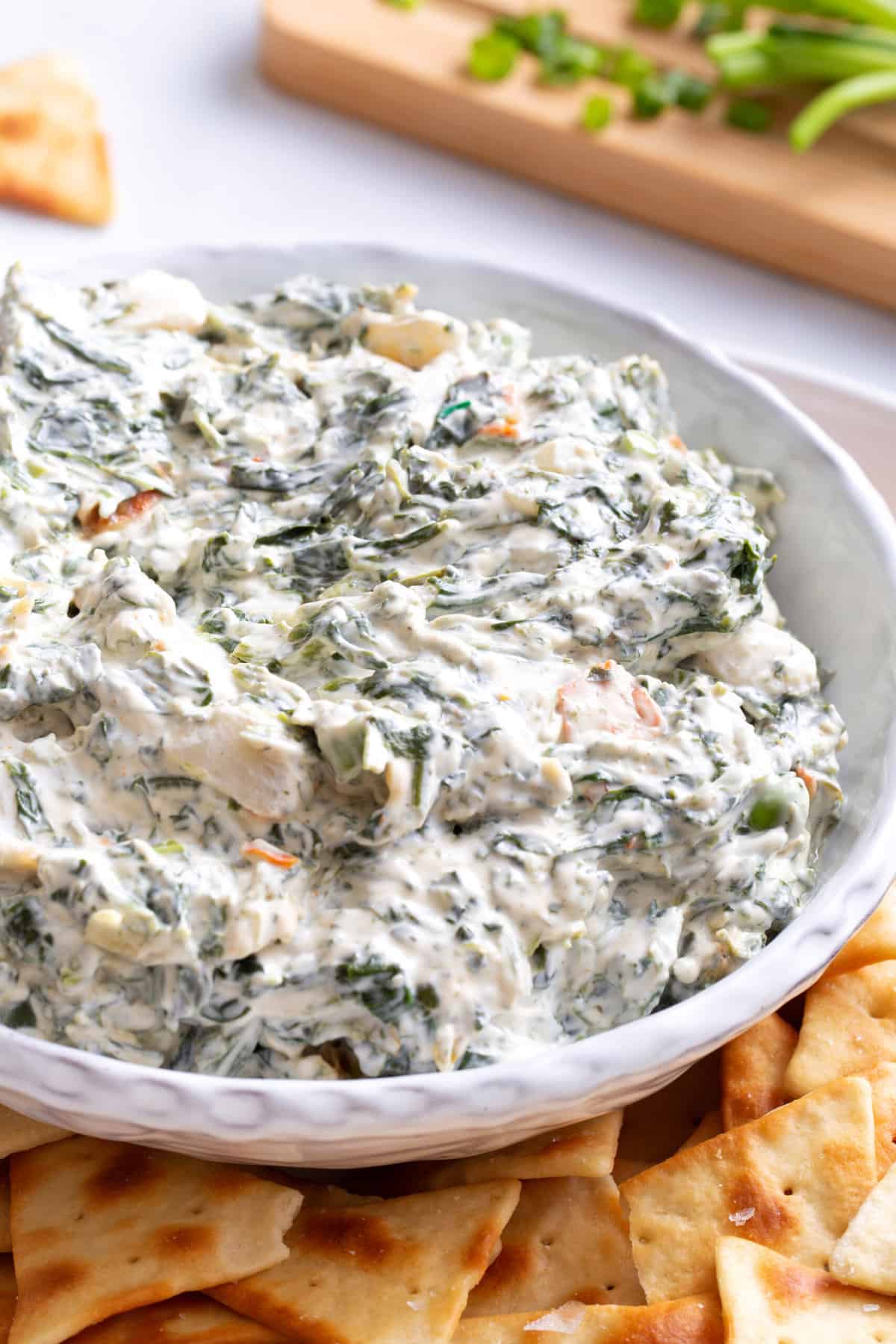 close up image of a bowl of spinach dip with a side of triangle shaped pita chips