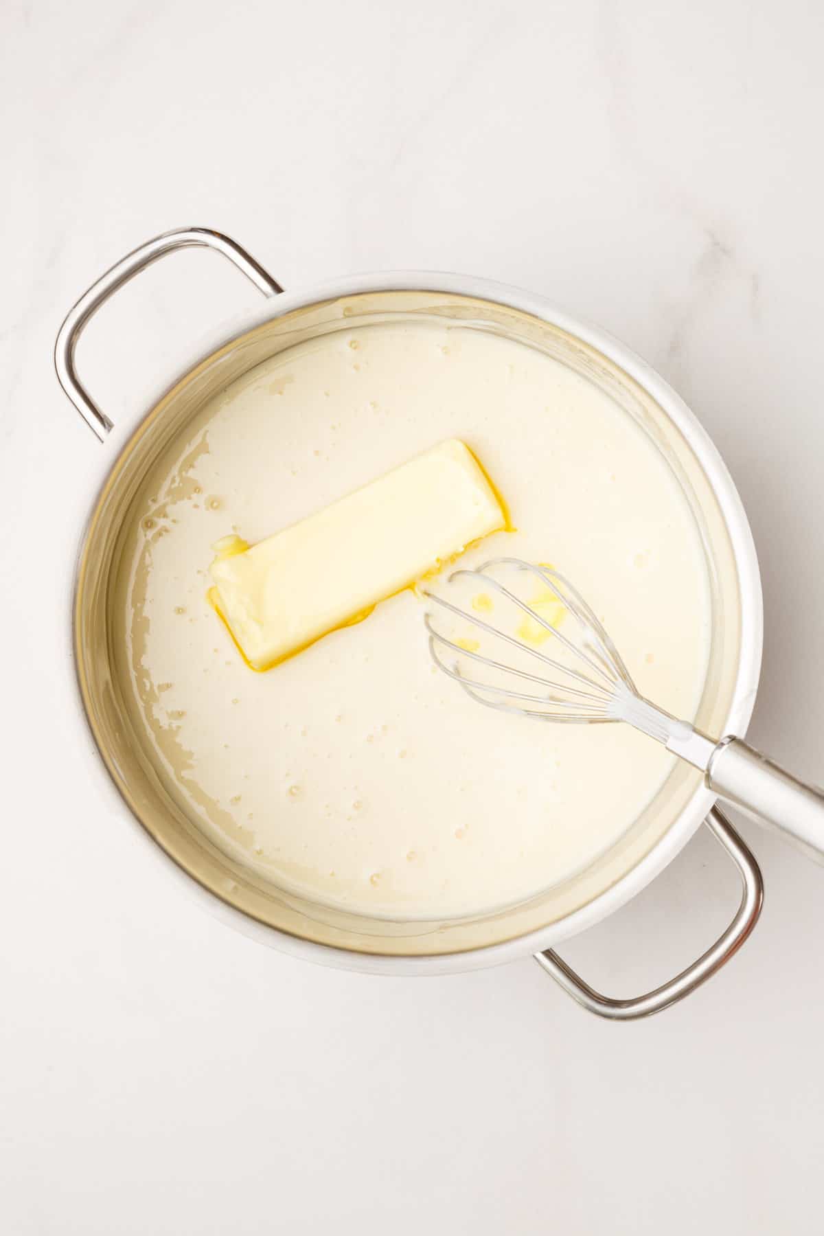 large pot with cream and butter with a metal whisk.