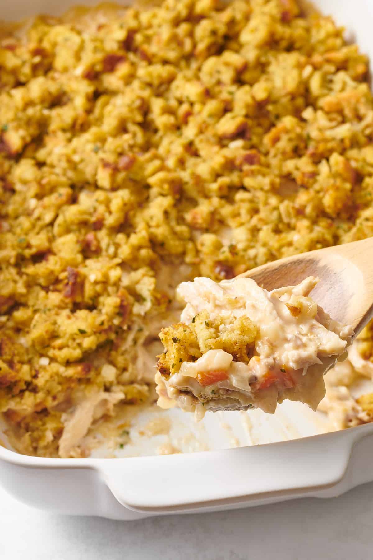 close up of a wooden spoonful of chicken and stuffing casserole. 