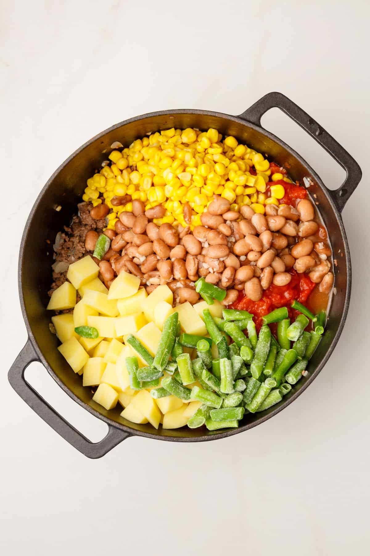 mixed vegetables, pinto beans, cooked ground beef, onion and garlic, and cubed potatoes in a large cast iron dutch oven