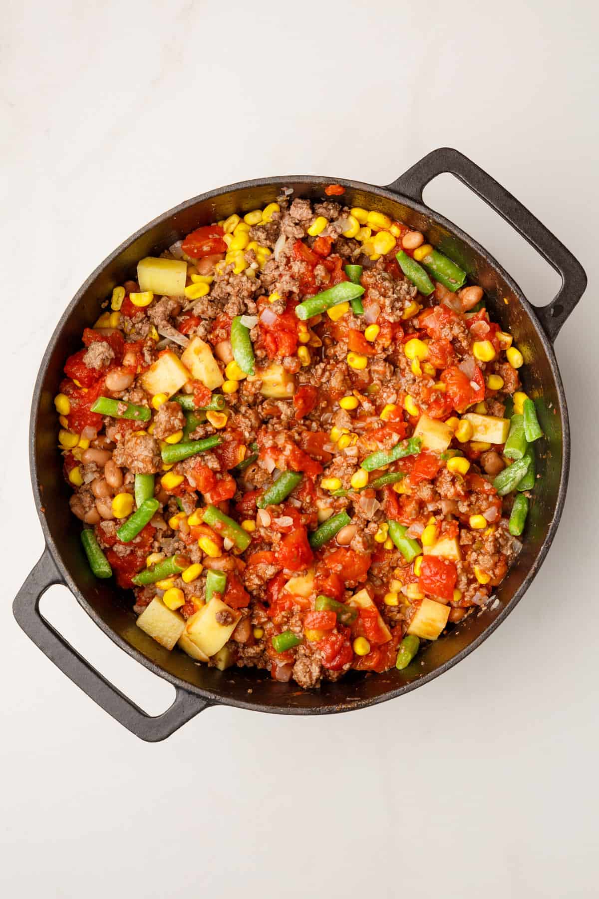 mixed vegetables and cooked ground beef in a large cast iron skillet