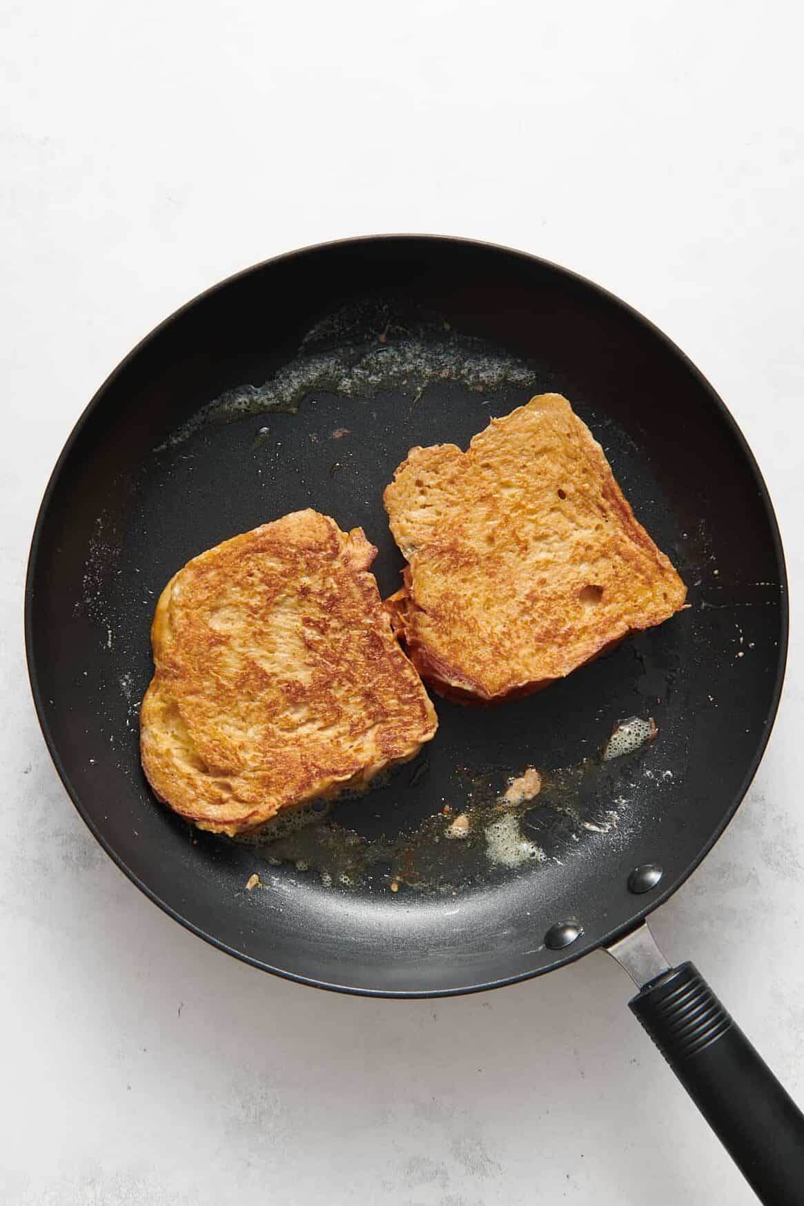 two eggnog french toasts cooking on a large skillet.