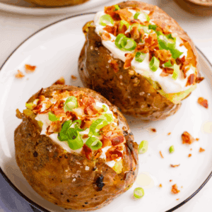 Two loaded baked potatoes on a plate.