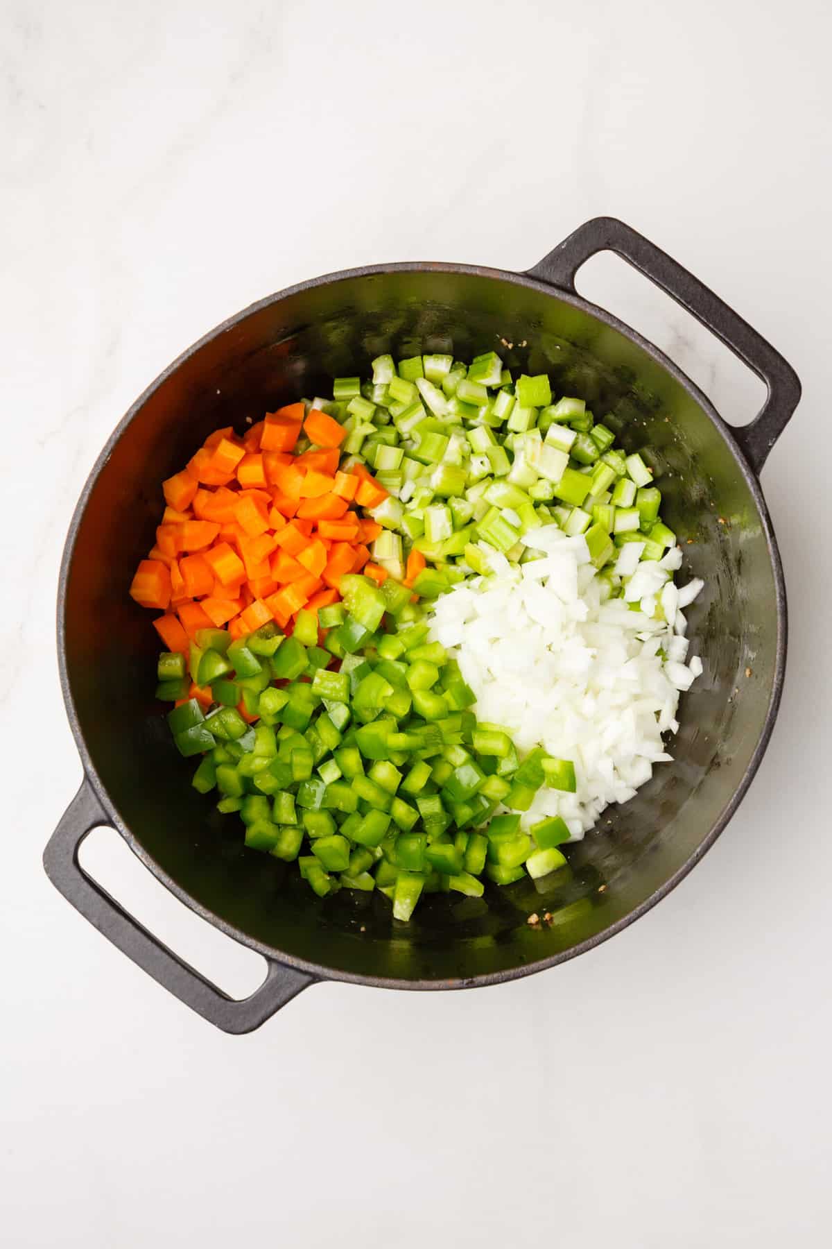 dutch oven with cooked chopped carrots, celery, green bell peppers, white onions