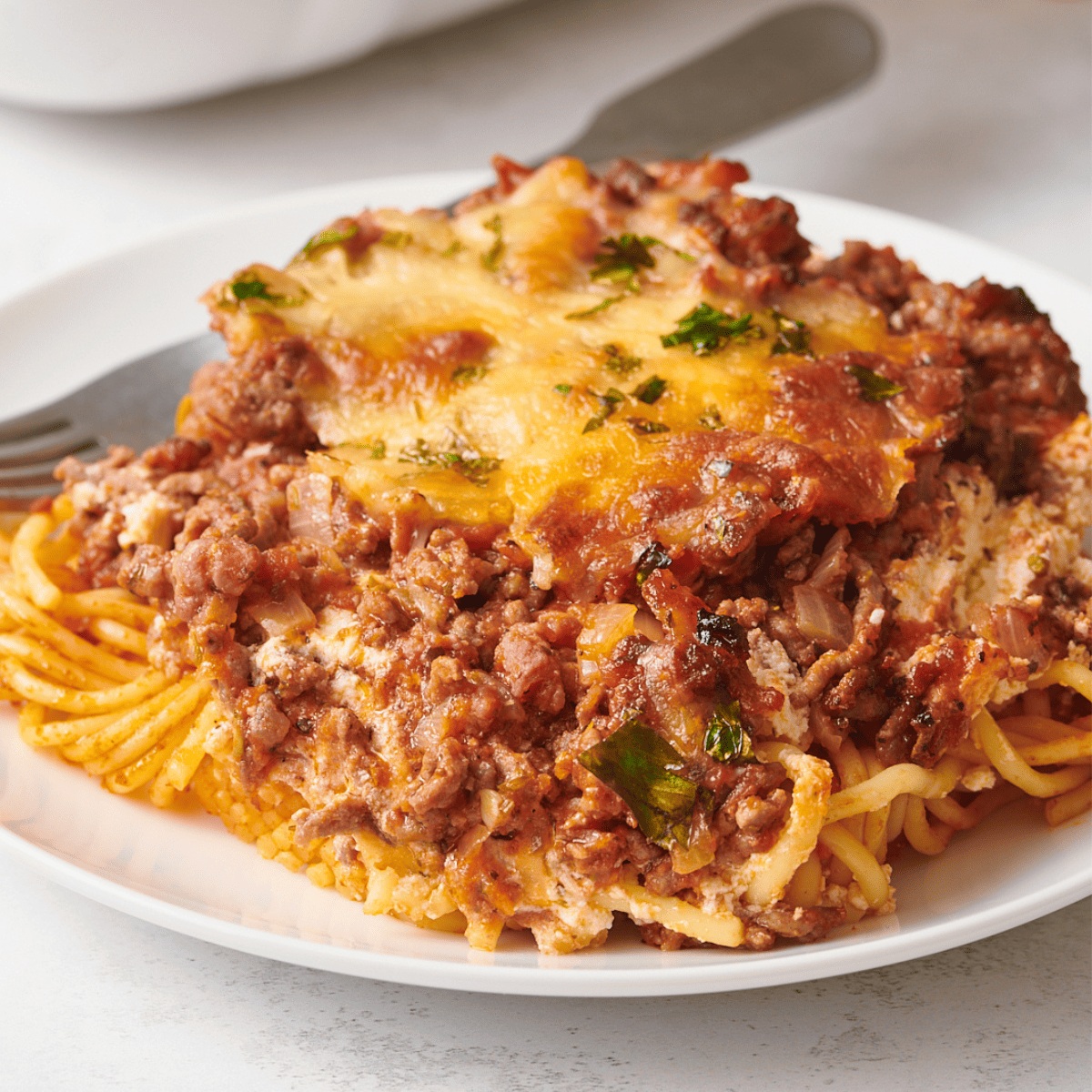 A large serving of million dollar spaghetti on a plate with a fork.