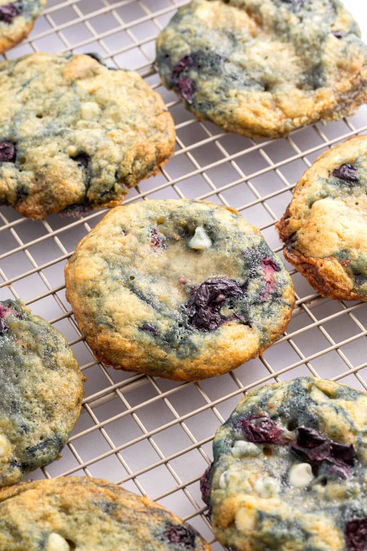 close up image of blueberry cookies sitting on a wire rack.