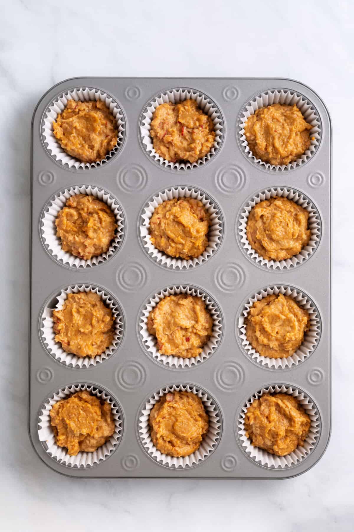 pumpkin muffin batter prepared in a muffin lined tin.
