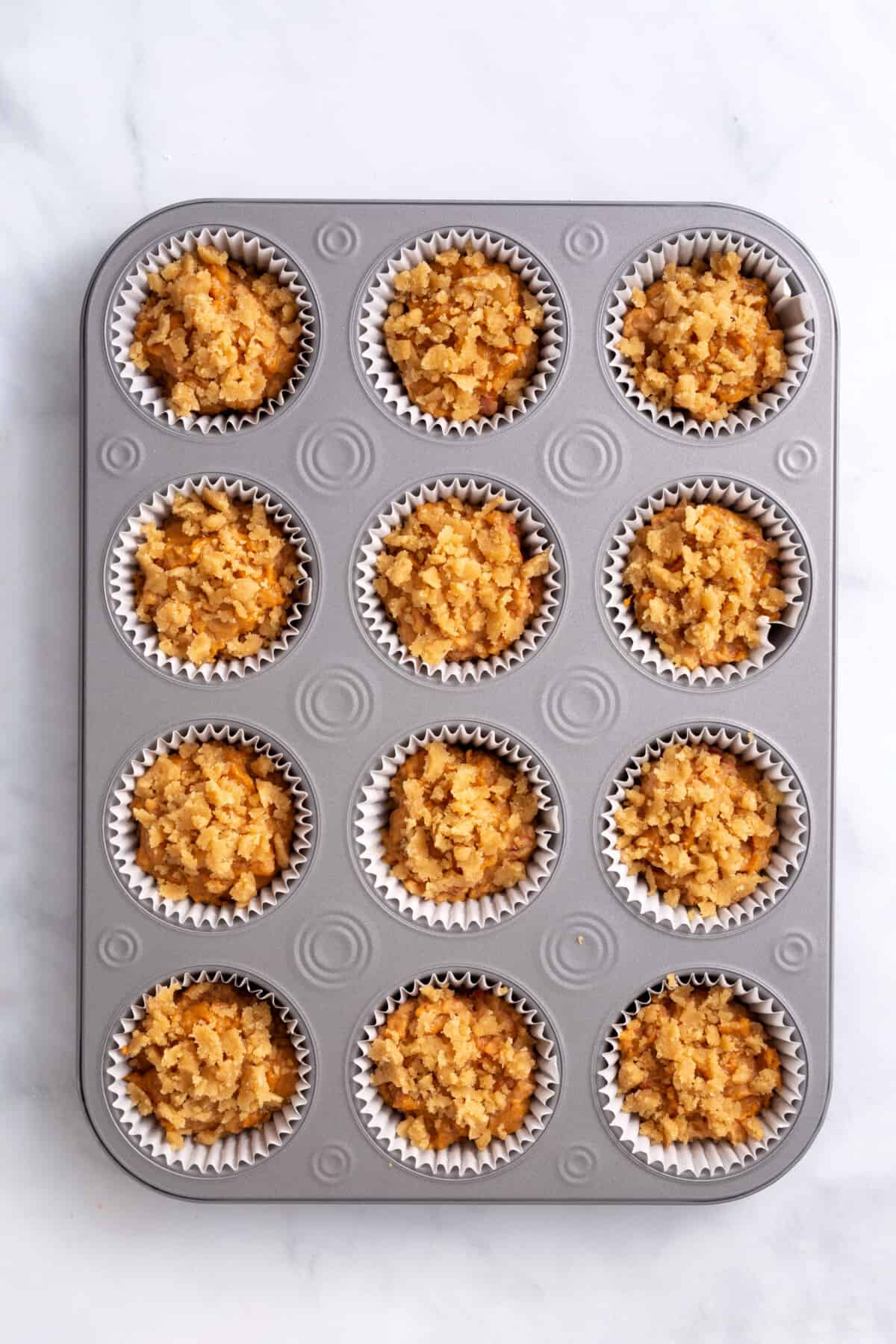 pumpkin muffin batter topped with crumble mixture prepared in a muffin lined tin.