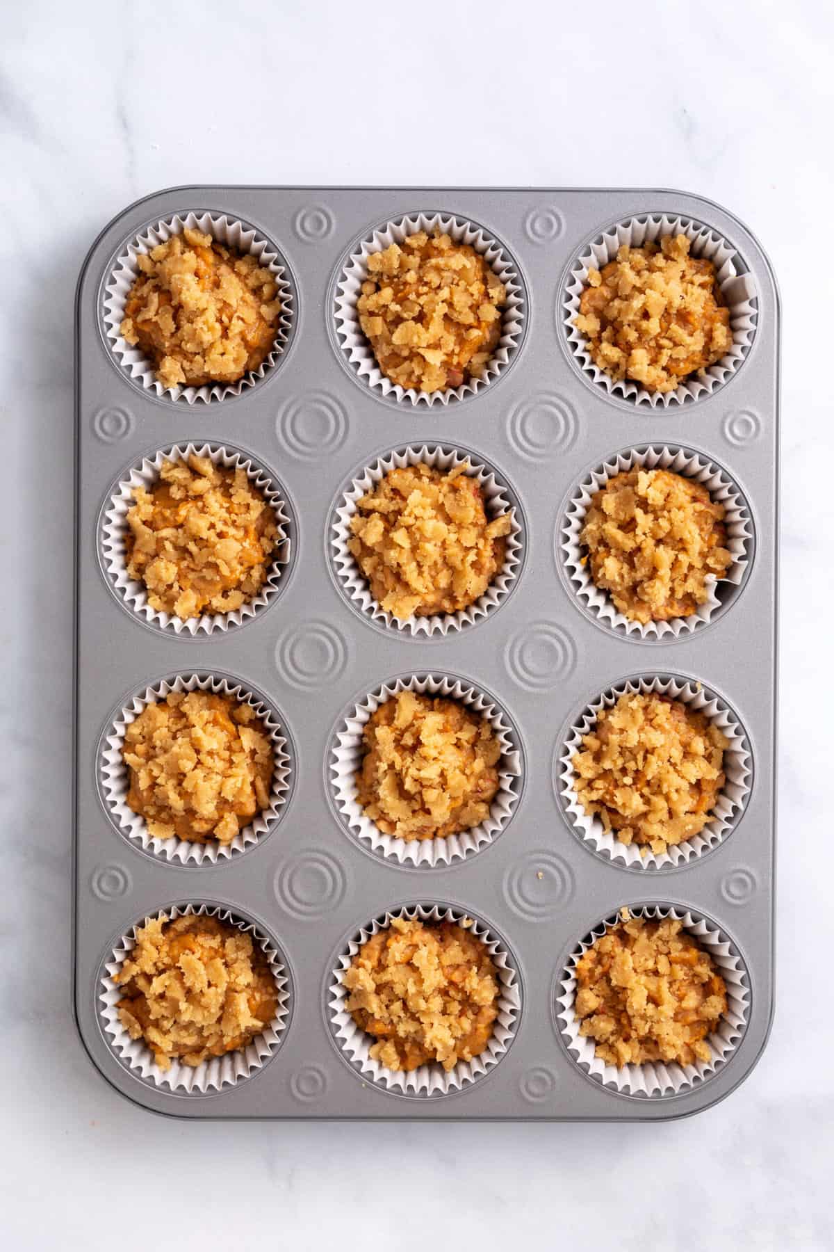 pumpkin muffin batter topped with crumble mixture prepared in a muffin lined tin
