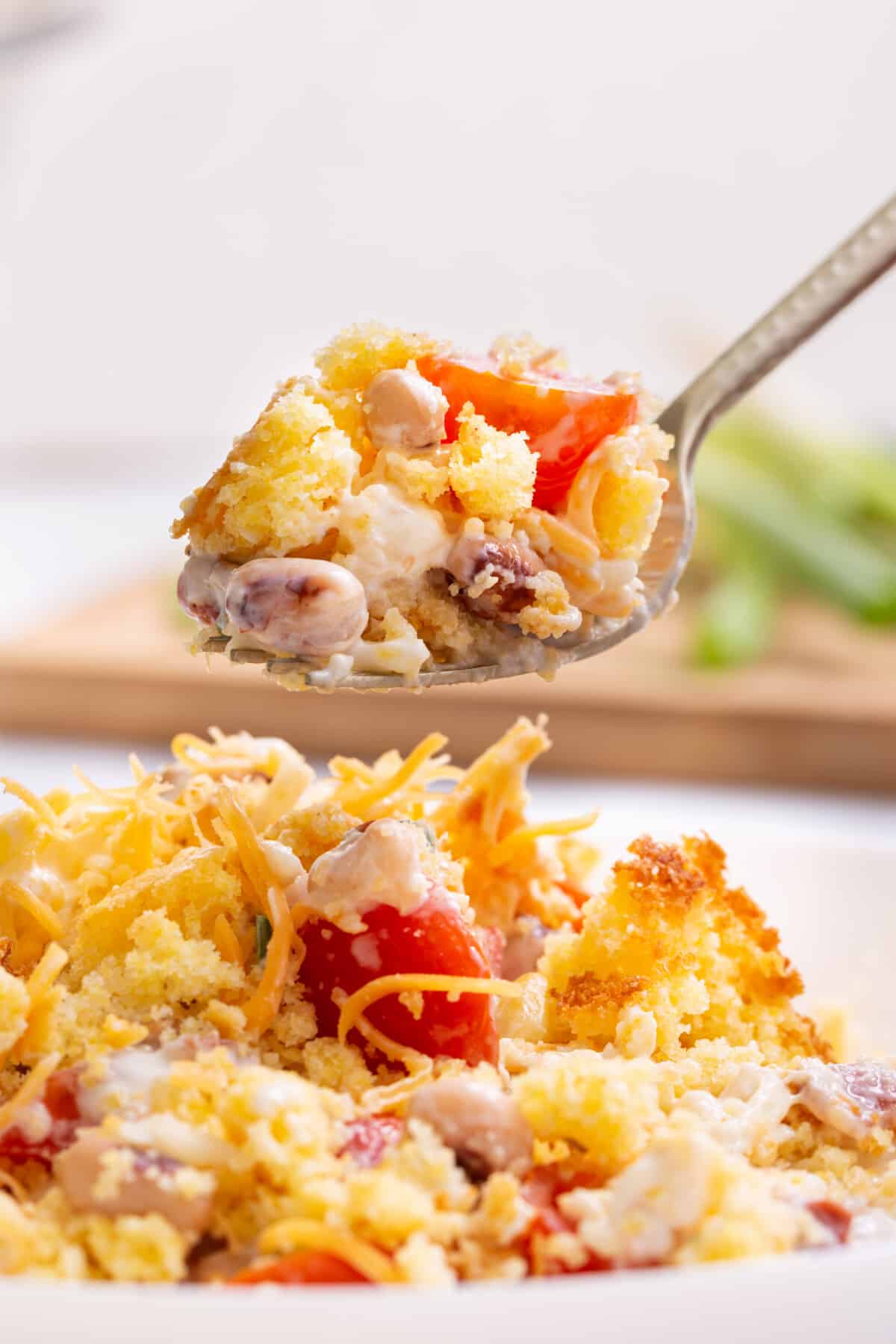 A spoon lifting a bite of Southern cornbread salad from a plate.
