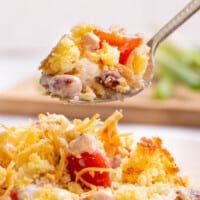 A spoon lifting a bite of Southern cornbread salad from a plate.