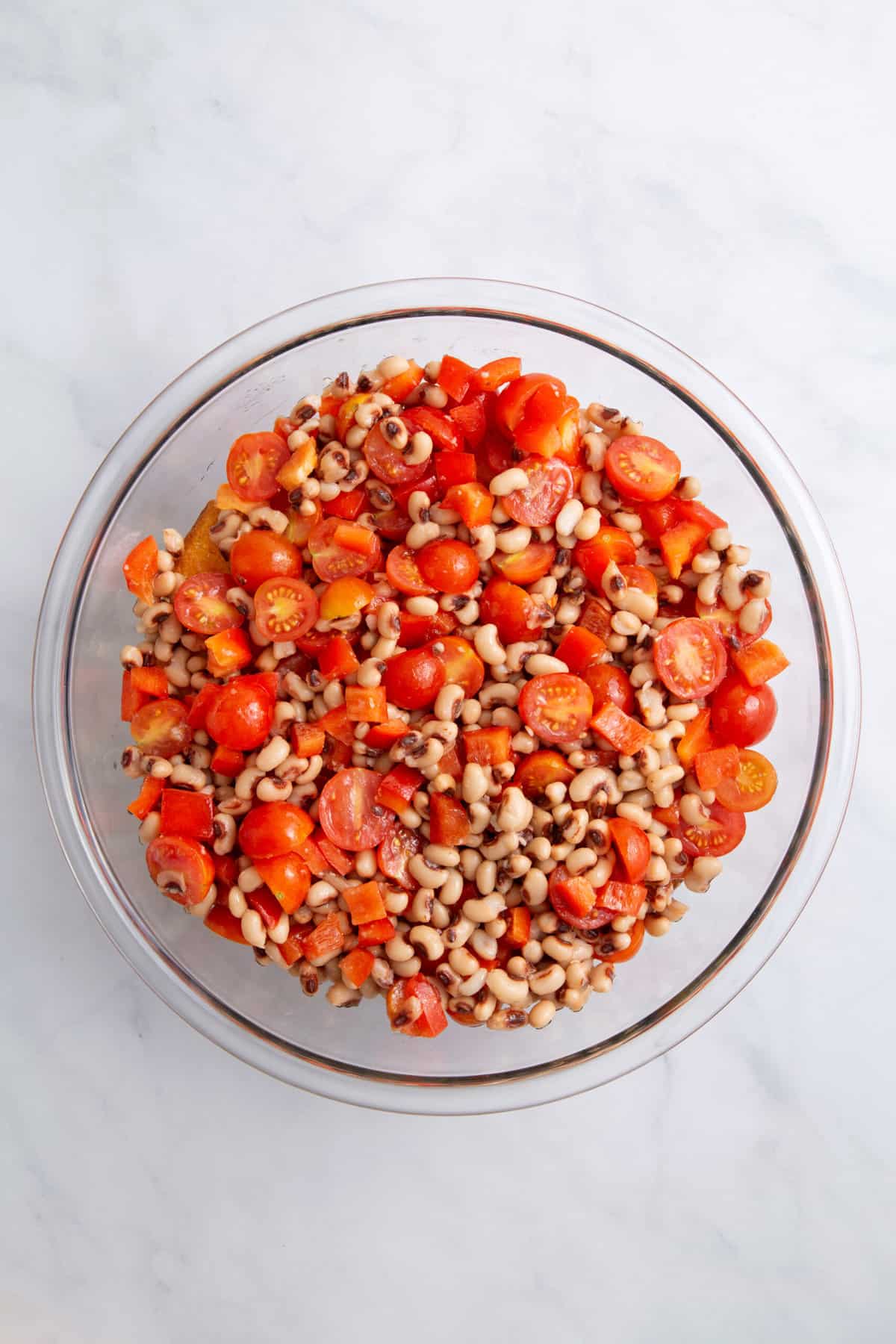 large glass bowl of black-eyed peas and halved cherry tomatoes.